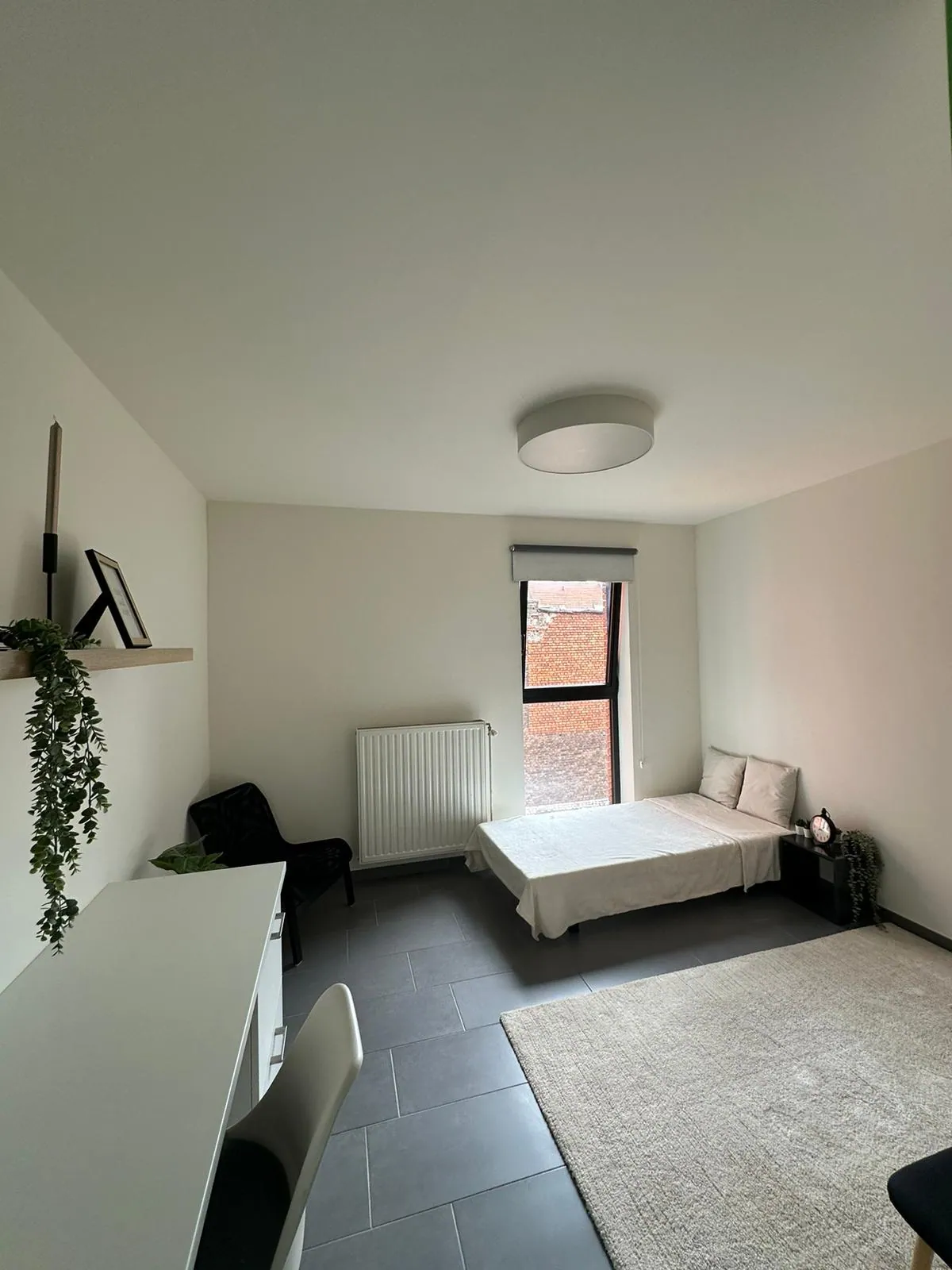 Ruime studentenkamer met bed aan het raam en eigen radiator